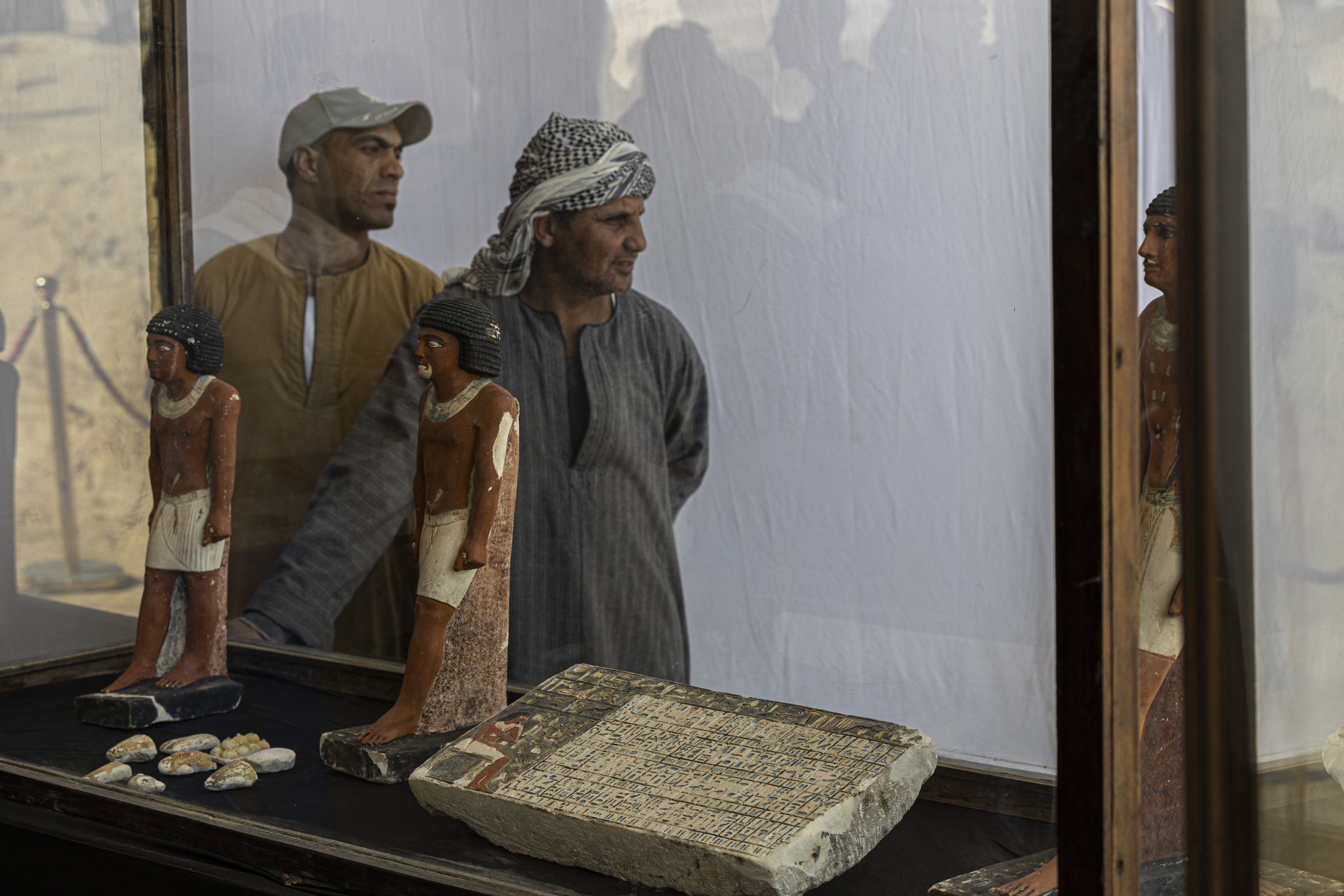 Workers stand behind a collection of pharaoh statues during a press conference at the Saqqara archaeological site, south of Cairo on January 26, 2023. /AFP