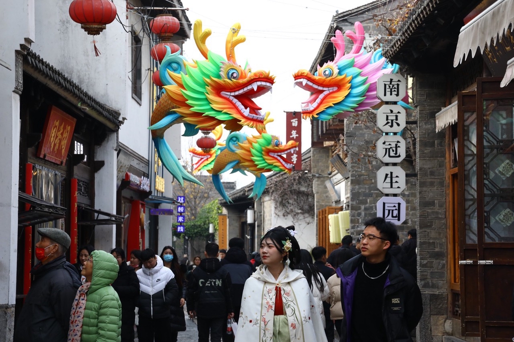 A photo shows pedestrians passing under dragon lantern decorations strung up in an alleyway in the Qinhuai District of Nanjing, Jiangsu on December 13, 2023. /IC