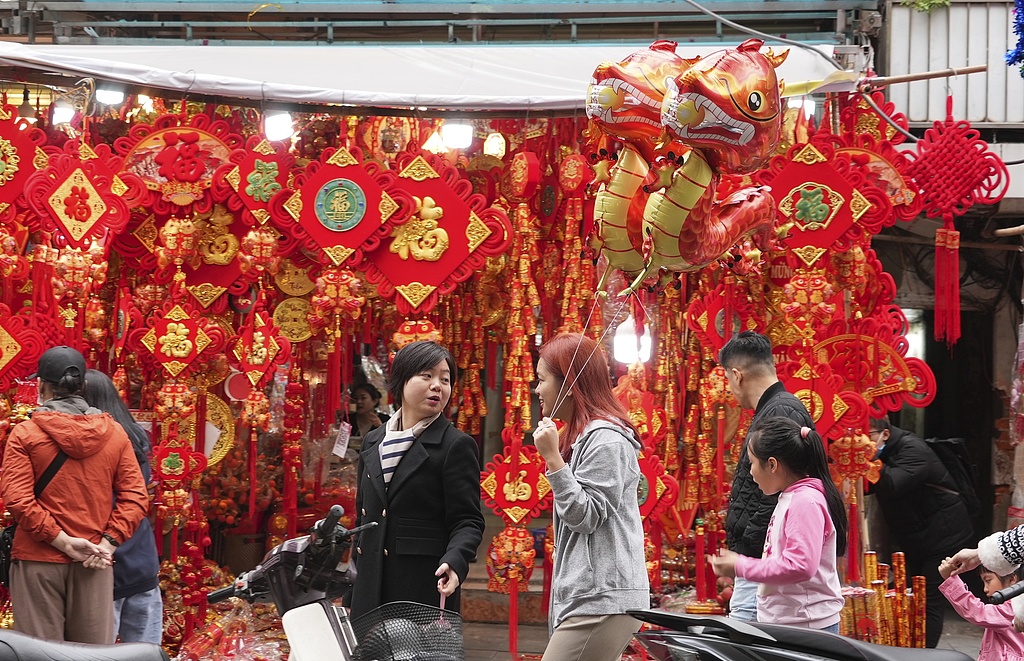 File photo of a woman holding dragon-shaped balloons as people shop for Spring Festival decorations in Hanoi, Vietnam Thursday, Feb. 8, 2024. /Huy Han/VCG