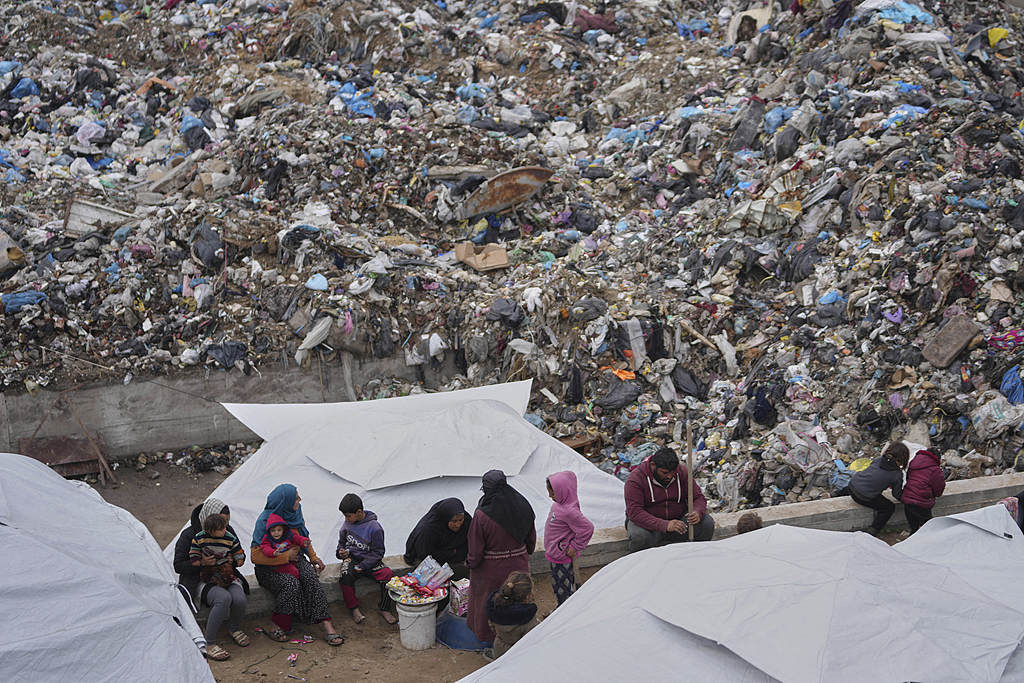 Palestinians displaced by the Israeli air and ground offensive on the Gaza Strip sit in a makeshift tent camp inside a landfill in central Gaza, March 21, 2025. /VCG