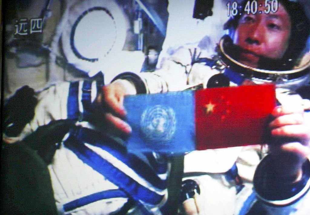 China's first spaceman Yang Liwei holds a United Nations flag next to a Chinese national flag in space on October 15, 2003. /VCG